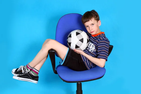 Jongen met voetbal op een stoel van het Bureau — Stockfoto