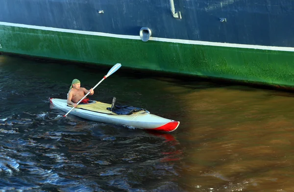 Um homem em um caiaque flutua ao lado do navio — Fotografia de Stock