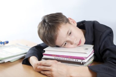 Öğrenci başını bir kitap yığını koymak.