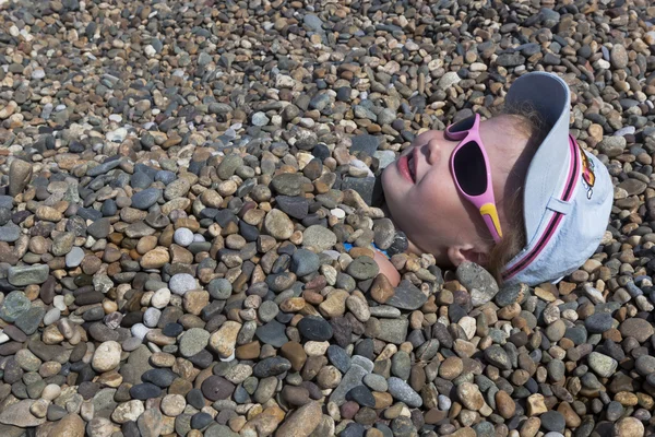 Meisje teruggestort kiezels op het strand — Stockfoto