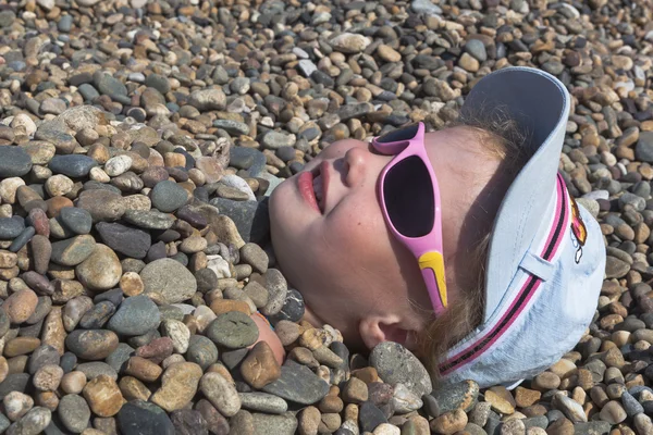 Huvudet flickor beströdd med stenar på stranden — Stockfoto