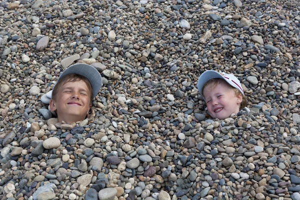 Happy kids on the beach covered with pebbles — Stock Photo, Image