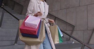 Açık havada renkli alışveriş torbaları taşıyan bir kadın alıcı.