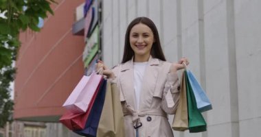 Alışveriş merkezinin yanında duran mutlu kadın.