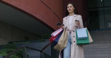 Alışveriş torbaları taşıyan ve cep telefonu kullanan bir kadın.