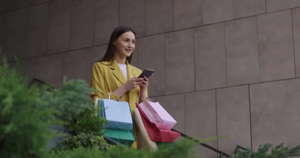 Nő bevásárló táskák sms-ező mobil szabadban — Stock videók