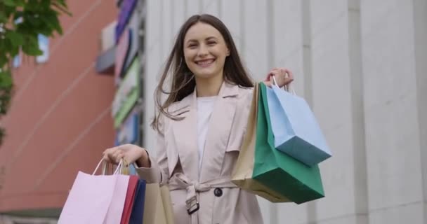Mujer sonriendo sinceramente con bolsas de compras en las manos — Vídeos de Stock