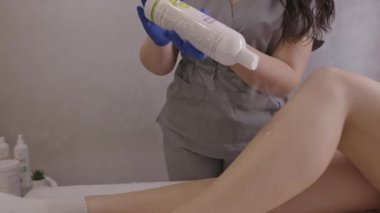 Beautician applying powder on female legs after sugaring