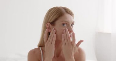 Older mature lady touching pampering face with hand. Middle aged womans face with perfect skin. Advertising of cosmetology salon rejuvenating spa procedures skincare 