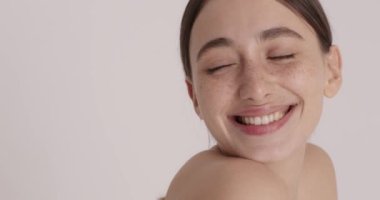 Freckled young woman with perfect skin laughing while doing beauty procedures and skin care treatment at home. Morning routine concept