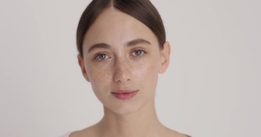 Close up portrait of a charming young woman smiling after applying moisturising face cream isolated on white studio wall. Self care concept 