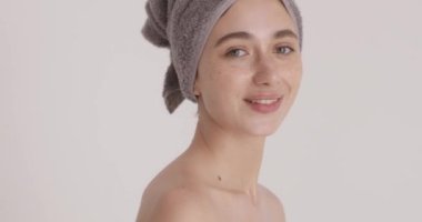 Stunning young woman smiling before applying moisturising creme on face, feeling happy of smoothing perfecting skin, enjoying daily skincare routine after shower 