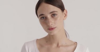 Sensitive woman with nude makeup showing her perfect face at the camera at studio with white background. Beauty and female appearance concept 