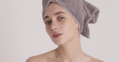 Sensitive perfect skin. Portrait of attractive nude lady wearing towel touching embracing her shoulder with pleasure after morning shower. Body skin care concept 