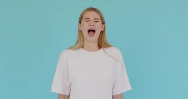 Angry mad young woman posing isolated on blue background in studio. People sincere emotions lifestyle concept. Looking at camera screaming scolding protest