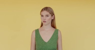 Portrait of displeased frustrated woman showing thumbs down, criticising dissatisfied with awful service. Indoor studio shot isolated on yellow background 