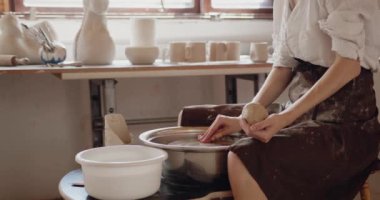 Modelling and sculpturing on pottery wheel. Cropped view of female artisan in art studio shaping jug from raw clay. Potter production for hobby entertainment or professional occupation and business 