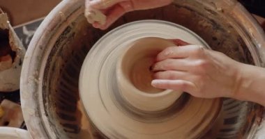 Cropped view of the female making clay pot on the ceramic wheel. Pottery girl is engaged in sculpting. Handicraft production, clay work concept 