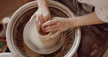 Cropped view of potters hands making beautiful handmade product on throwing wheel in pottery workshop. Creativity and traditional crafts concept 