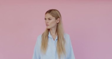 Woman keeping hand near ear to listen better, having hearing problems, difficult to understand. Indoor studio shot isolated on pink background 