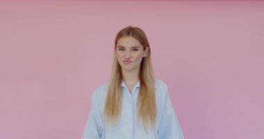 Dislike. Portrait of displeased frustrated woman showing thumbs down, criticising dissatisfied with awful service. Indoor studio shot isolated on pink background 