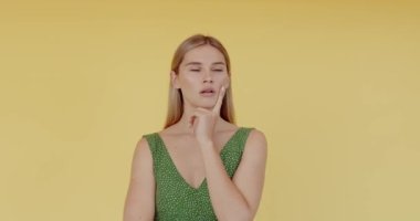 Ciddi genç bir kadın parmağını sıkar ve sarı arka planda poz verirken hayır der. İnsan duyguları kavramı