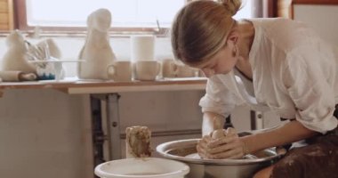Potter stüdyosunda çalışıyor. Çömlek çarkında çiğ çamurdan yapılmış bir kız. Kadın eli, seramikçi el yapımı balçık malzemesi modelliği yapıyor. Zanaatkar seramik konsept yaratıyor 