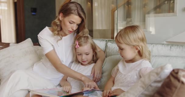 Jovem Atraente Abraçando Crianças Pequenas Lendo Livro Papel Juntos Sofá — Vídeo de Stock