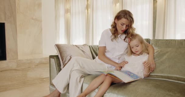 Attraente Giovane Donna Coccola Bambina Leggendo Libro Carta Insieme Comodo — Video Stock