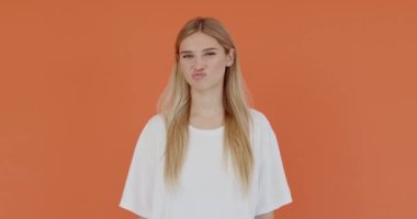 Berbat servis. Hoşnutsuz bir kızın portresi baş parmağını aşağı gösteriyor ve tiksintiyle yüzünü buruşturuyor, onaylamadığını ifade ediyor, kötü geri bildirim yapıyor. Turuncu arka planda kapalı stüdyo çekimleri 