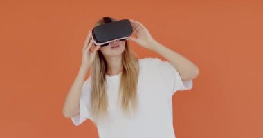VR kulaklık takan genç bir oyuncunun portresi elleriyle havaya dokunuyor, ciddi şekilde konsantre bir ifadeyle sanal gerçeklik oyunu oynuyor. Stüdyo içi çekim, izole. 