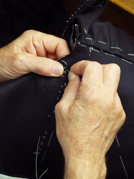 Mãos de alfaiate cosendo um casaco — Fotografia de Stock