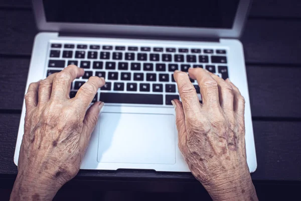 old persons hands on laptop keyboard