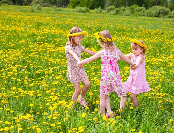 Niños jugando en un campo de diente de león — Foto de Stock