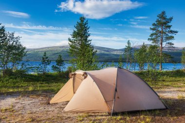Göl kıyısındaki kamp alanında kamp çadırı. Arka planda dağ sıraları var. Vahşi kamp konsepti.