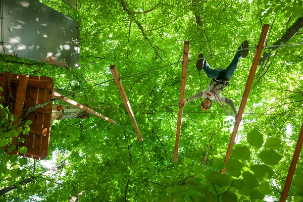 Criança em um parque de aventura na copa da árvore — Fotografia de Stock