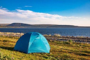 Arktik Okyanusu kıyısındaki kamp alanında kamp çadırı. Arkaplanda dağ sıraları var. Vahşi kamp kavramı.