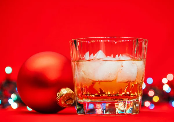 Close Shot Glass Whiskey Rocks Christmas Baubles Blurred Lights Red — Stock Photo, Image