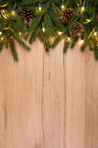 木製ボード上のモミの枝コーンやライトとクリスマスの背景 — ストック写真