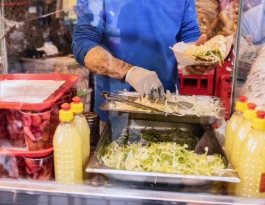 Aşçı geleneksel Türk sokak yemekleri yapıyor Balik Ekmek kızarmış uskumru filetosunu Türk ekmeğinin içinde sebzeyle karıştırıyor