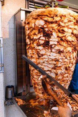 Türkiye 'nin İstanbul kentinde ızgara tavuk etini dönüşümlü tükürükten kesen aşçı geleneksel Türk sokak yemekleri Doner Kebap (Şavurma veya Gyros) yapıyor