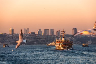 İstanbul Boğazı 'ndan gün batımında feribotla geçen yolcu. Arka planda Beyoğlu ilçesi görülüyor