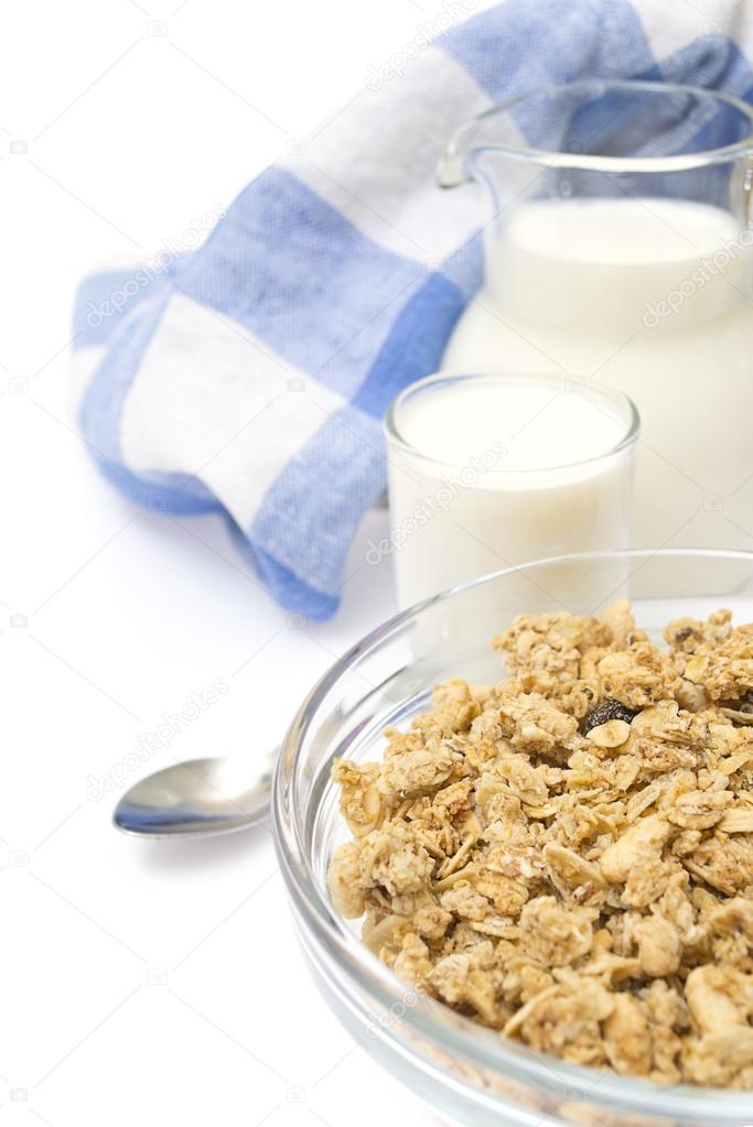 Close-up of a bowl of cereal with a jug of fresh milk, isolated