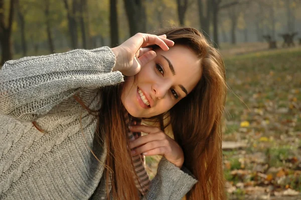 Mujer sonriente quitándose el pelo de la cara en el parque de otoño —  Fotos de Stock