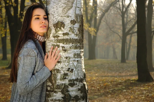 Pensive woman leaned on birch in autumn park — Stock Photo, Image