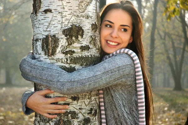 Žena s úsměvem a objímání břízy — Stock fotografie