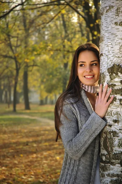 Mujer sonriendo, apoyada en un abedul —  Fotos de Stock