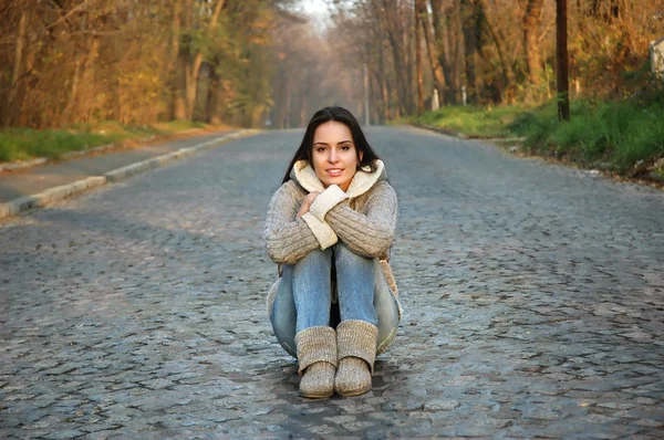 Jovem mulher sentada no meio de uma estrada velha — Fotografia de Stock