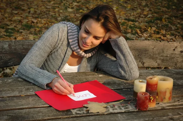 Kobieta pisze słowo miłość, papier na drewnianym stole — Zdjęcie stockowe