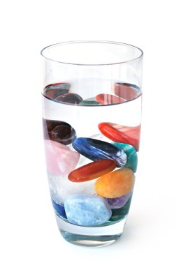 Crystals in full filled glass of water, on white clipart